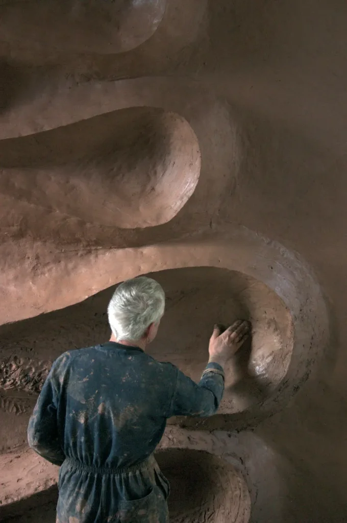 Andy Goldsworthy shaping the clay wall of Refuge d'Art Vieil Esclangon with his bare hand, La Javie, Haute-Provence, 2005