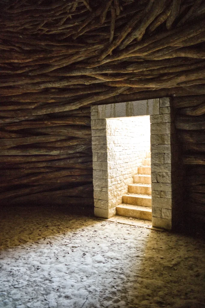Interior of Andy Goldsworthy's Oak Room at Chateau La Coste, a low chamber roofed with interlocking oak branches, light falling through the stone doorway