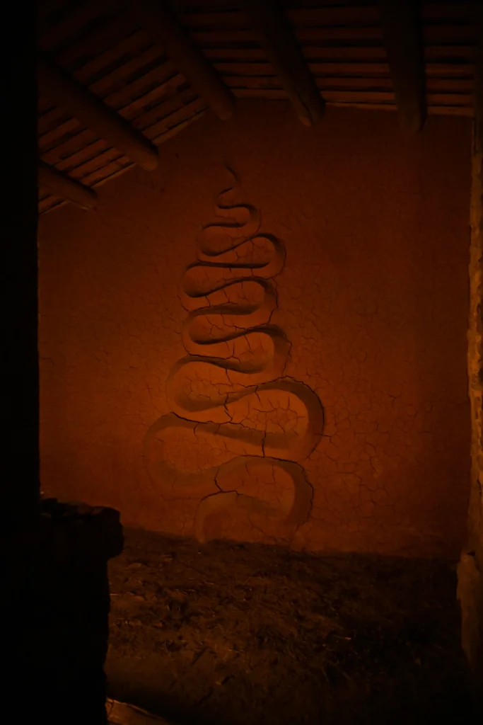Andy Goldsworthy's serpentine clay relief inside Refuge d'Art Vieil Esclangon by candlelight, the chestnut ceiling above