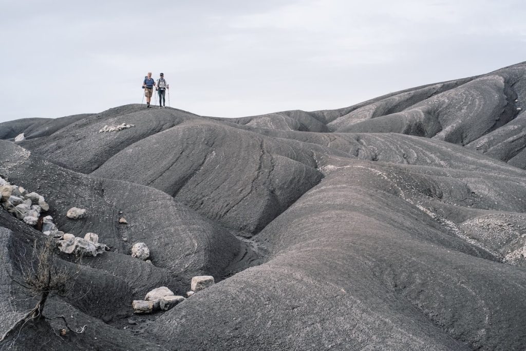 Walkers crossing the lunar black marl landscapes near Draix, spectacular geology of the Alpes-de-Haute-Provence