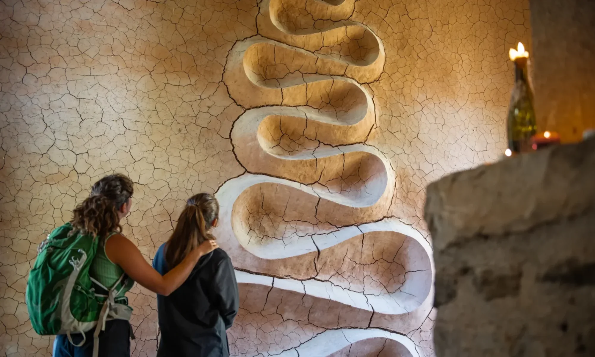 Deux randonneuses découvrent le serpent d'argile d'Andy Goldsworthy dans le Refuge d'Art du Vieil Esclangon, collection d'art en montagne du musée Gassendi, Haute-Provence