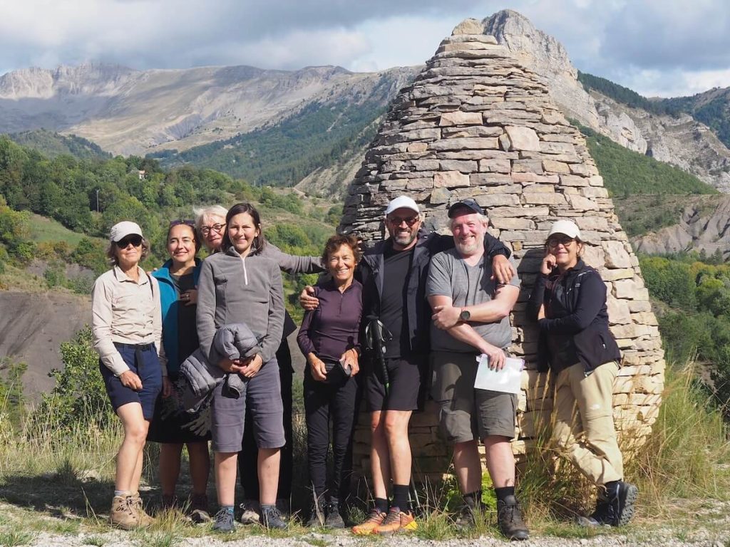 Small group of walkers on an art walking holiday in Haute-Provence, in front of an Andy Goldsworthy Sentinelle