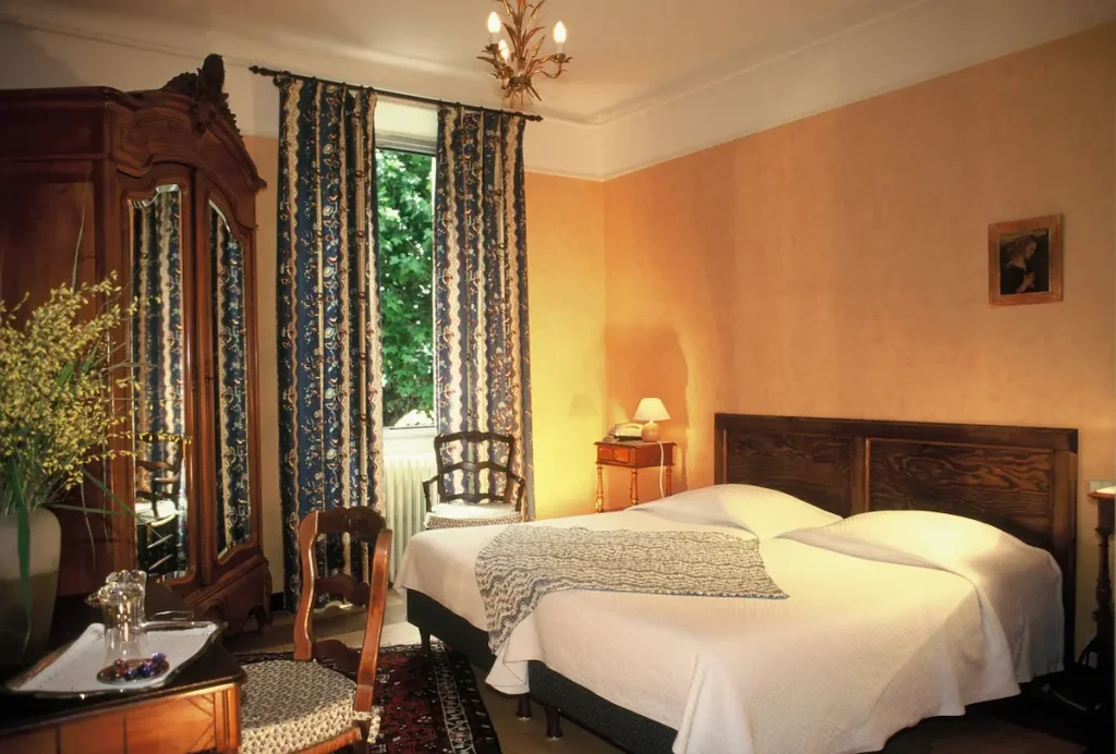 Bedroom at Villa Gaia, an eighteenth-century country-house hotel near Digne-les-Bains, with Provencal walnut furniture and a window onto the garden