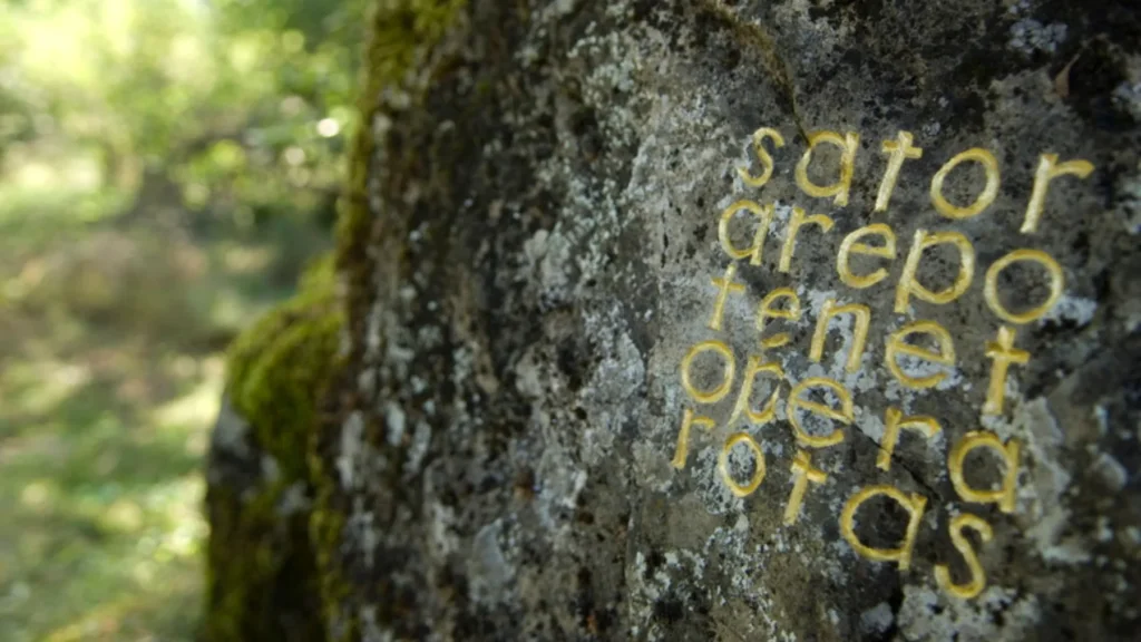 Lateinisches Palindrom sator arepo tenet opera rotas in Blattgold auf einem flechtenbewachsenen Felsen oberhalb von Digne-les-Bains